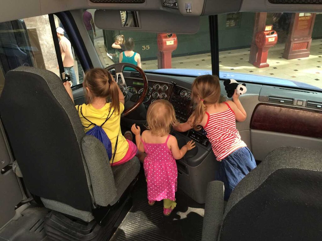 kids playing in the front of a postal mail truck.