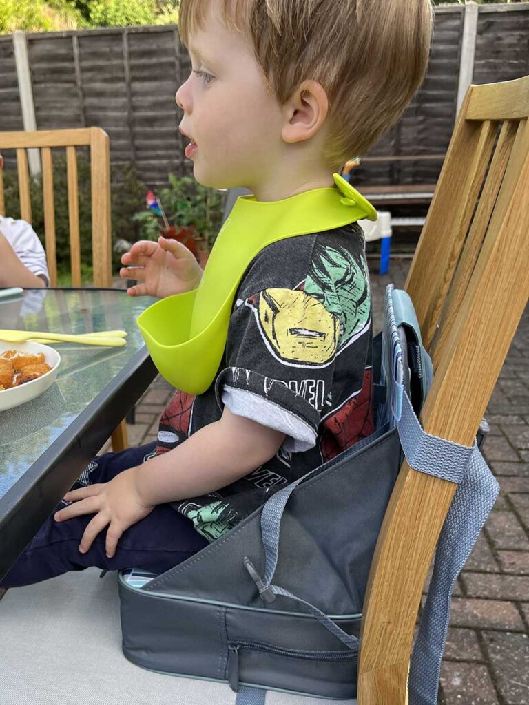 toddler using Nuby Easy Go Booster Seat at Restaurant.