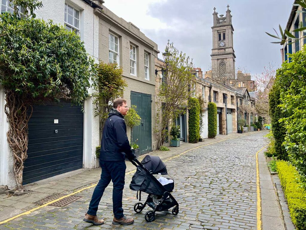 Man walking on cobblestone street with ErgoBaby Metro+ Stroller for travel.