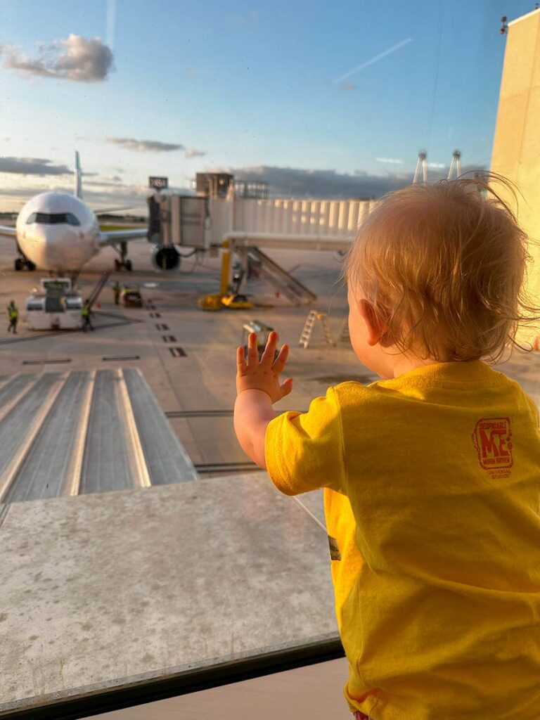 Baby staring out a window at a plane on the way to disney world with a baby or toddler.