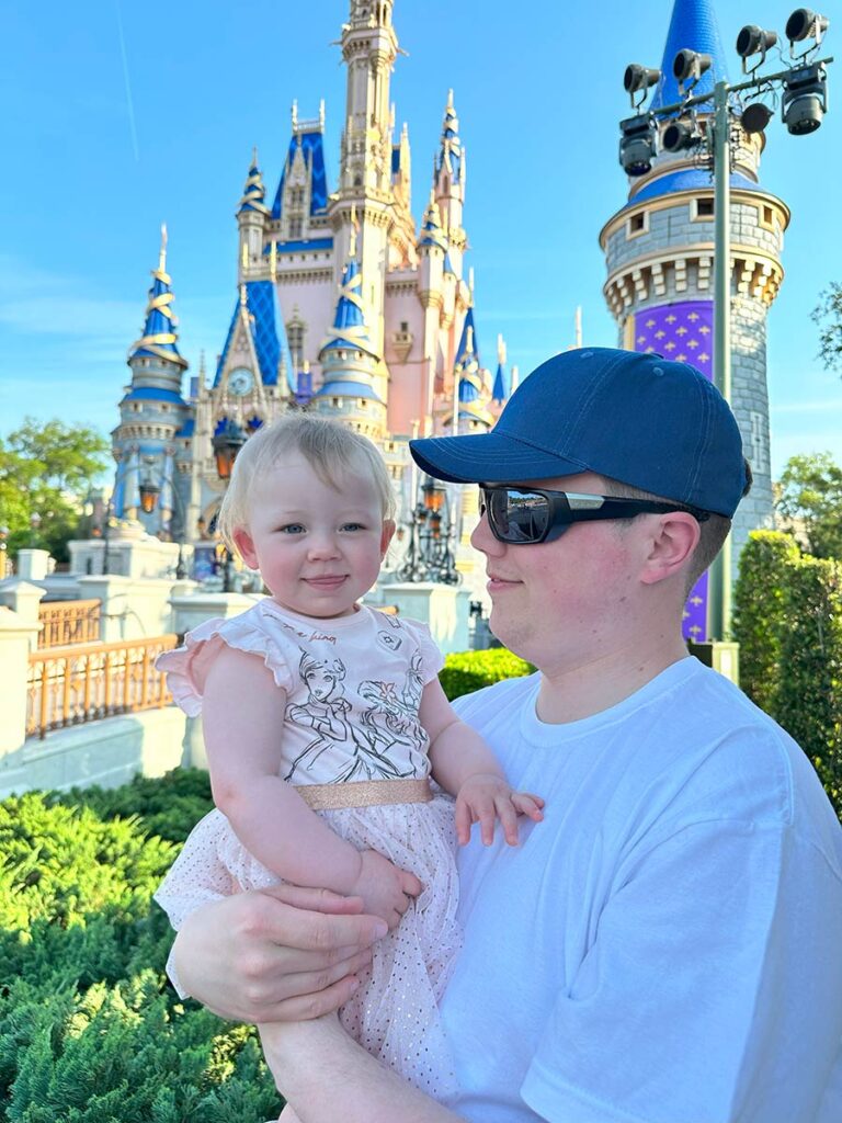 Dad and baby in front of Cinderella's Castle at Disney.