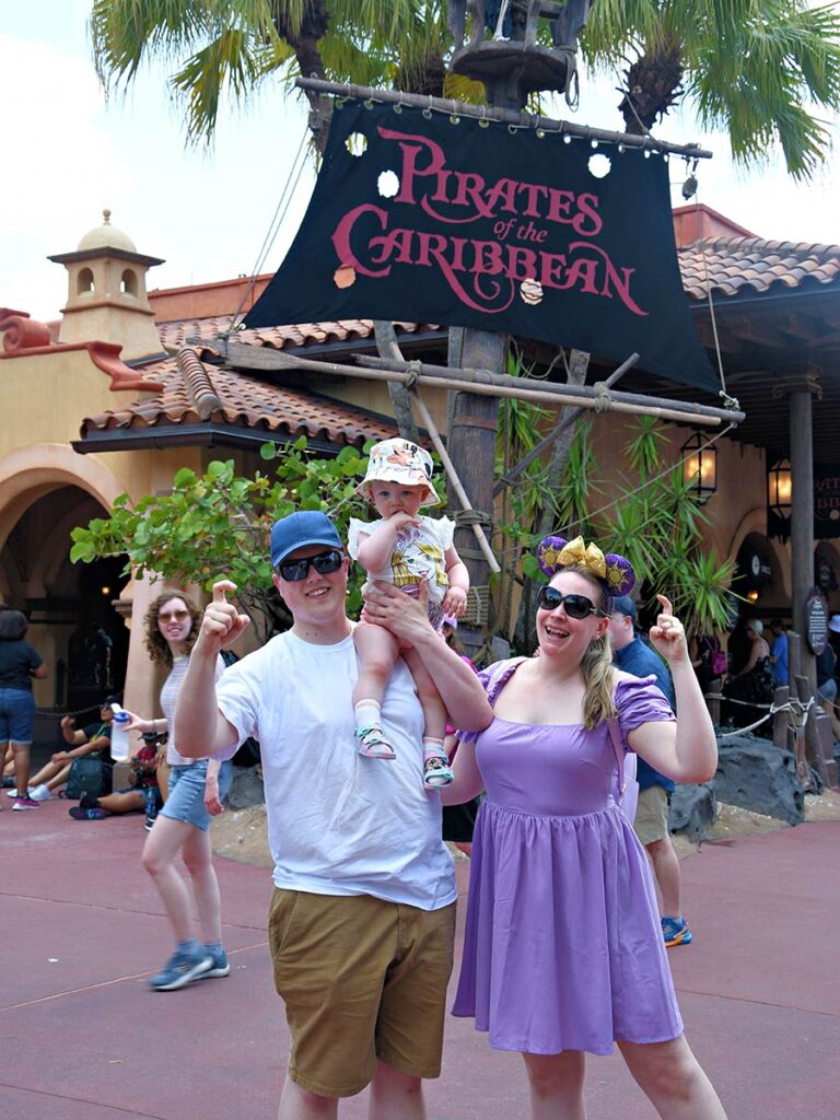 Family posing for a photo  in front of a ride at Disney.