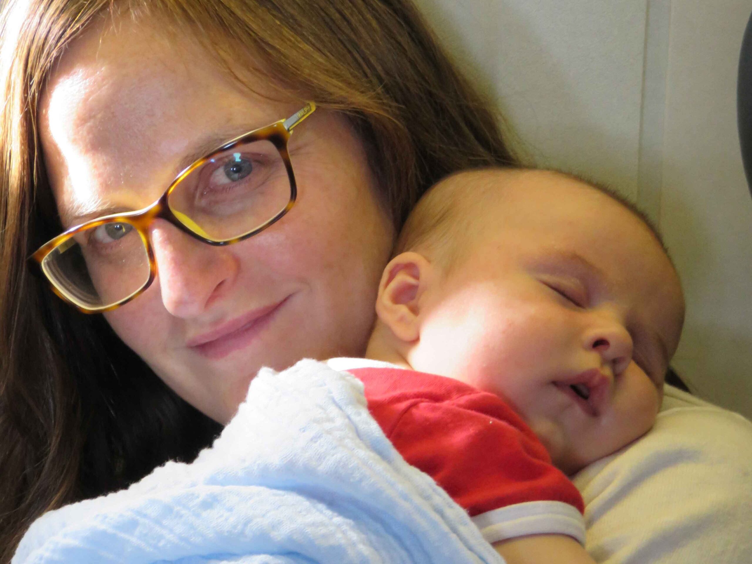 Baby asleep on mother on a flight.