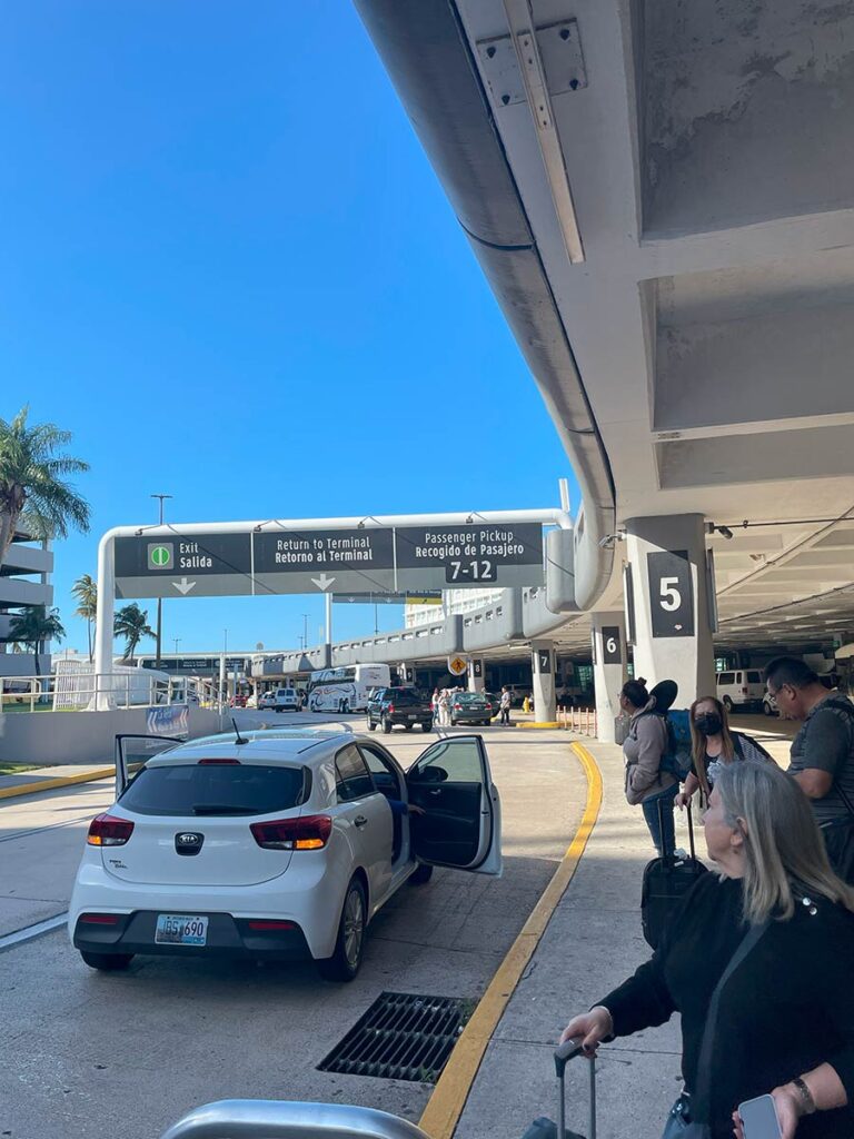 White car with doors open outside airport in San Juan, Puerto Rico.