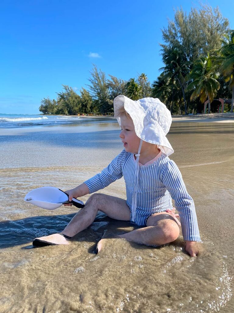 Toddler playing with scoop at the beach.