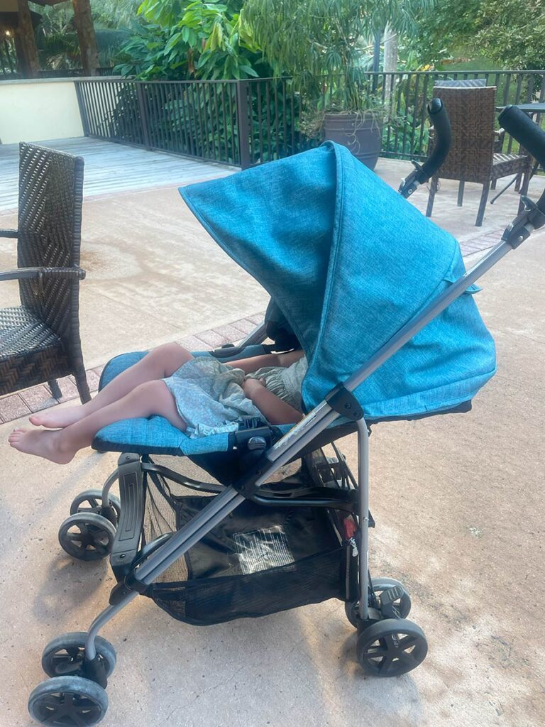 Stroller with a toddler reclined in it. 